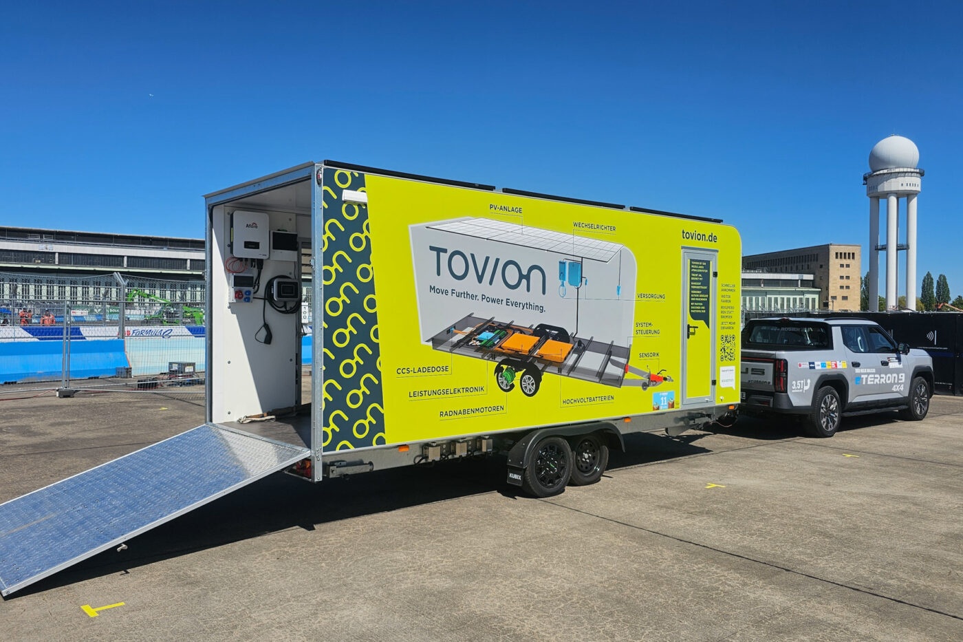 Yellow Tovion trailer with open rear ramp parked outdoors.