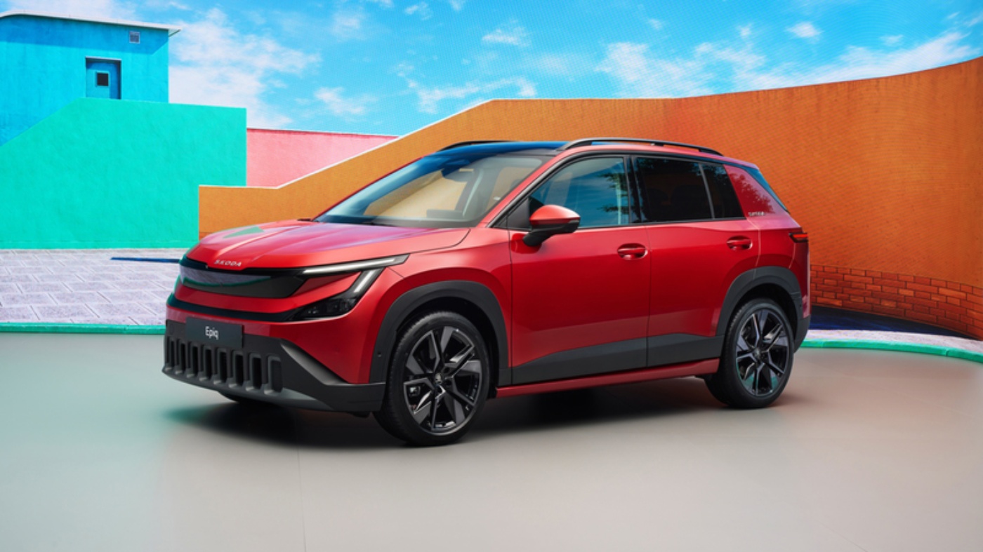 Red Škoda Epiq SUV parked in front of colorful modern buildings.