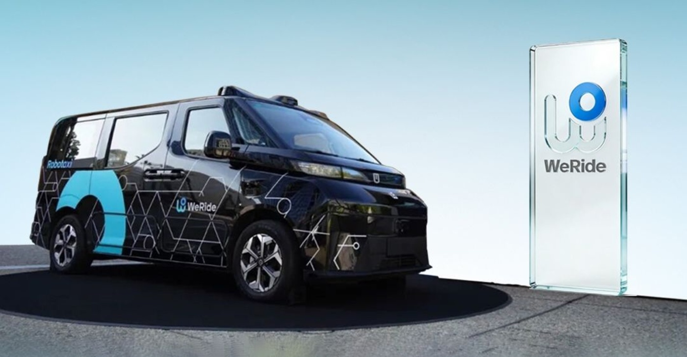 Autonomes WeRide Fahrzeug neben einem Schild mit WeRide Logo.