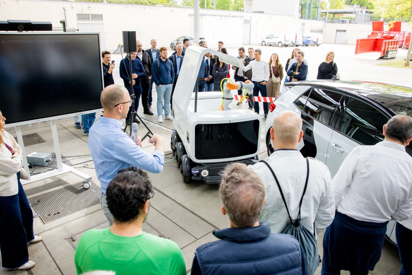 Group of people watching a Volkswagen vehicle demonstration at an outdoor event.