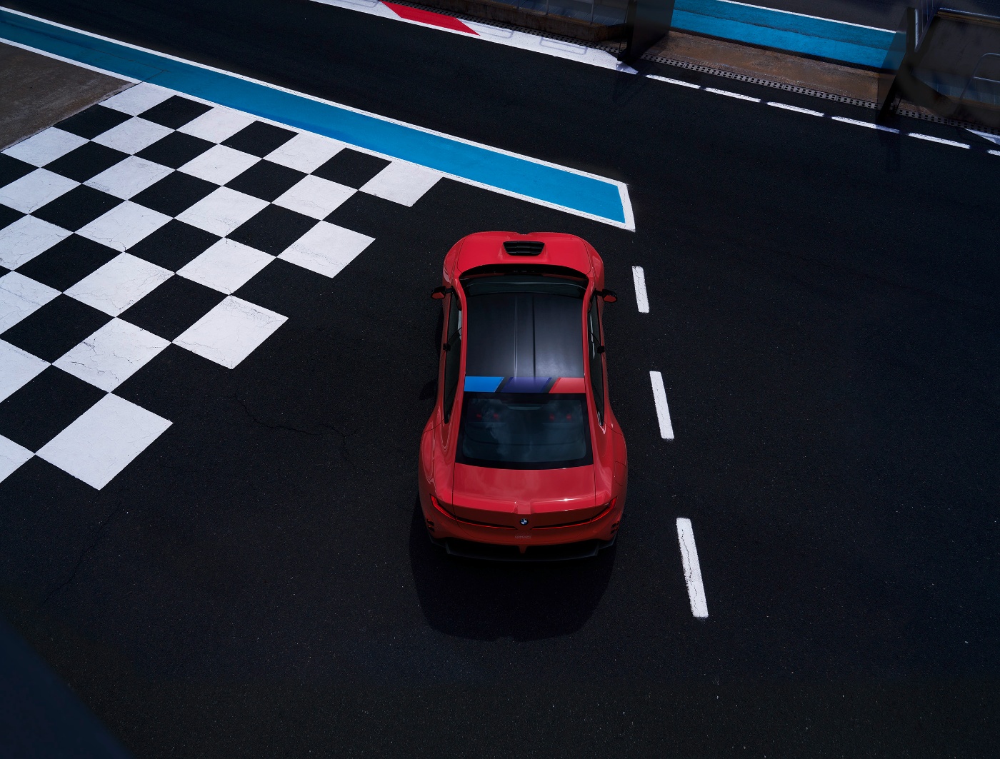 Red BMW viewed from above on a track with a checkered finish area.