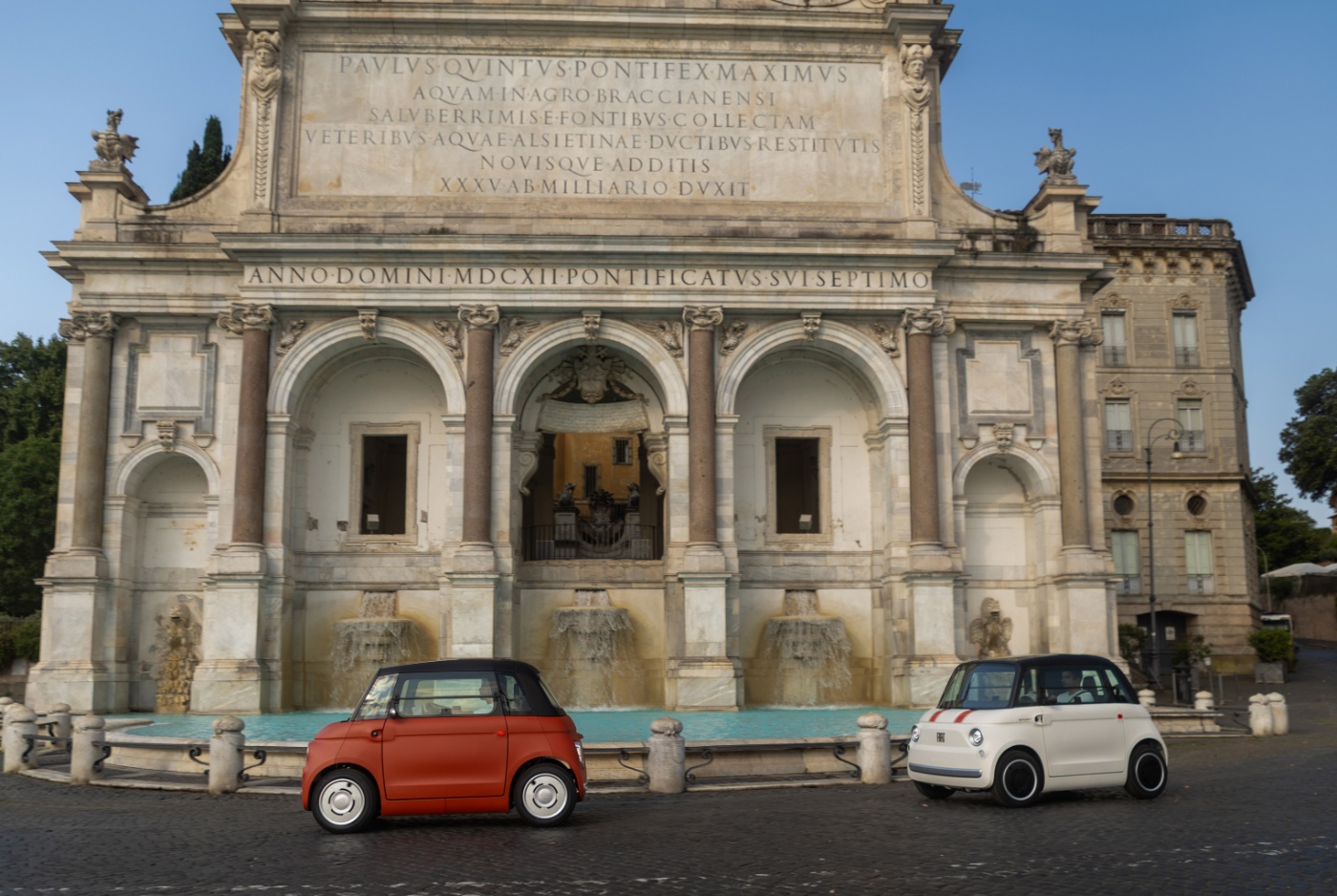 Zwei kompakte Fiat-Konzeptautos stehen vor einem historischen Brunnengebäude.