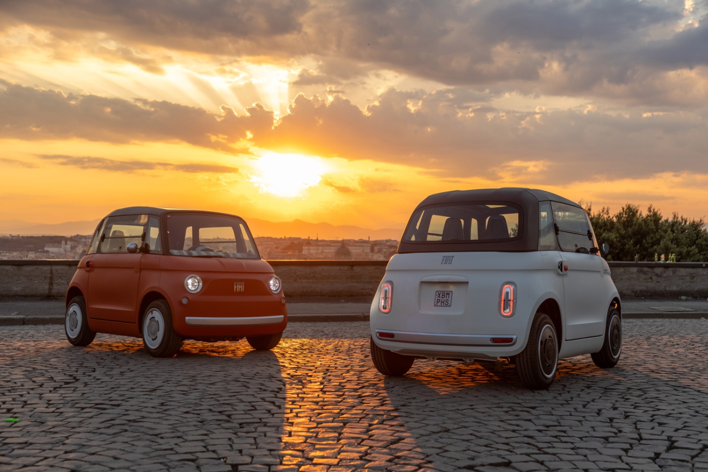 Zwei kompakte Fiat-Konzeptautos stehen bei Sonnenuntergang auf Kopfsteinpflaster.