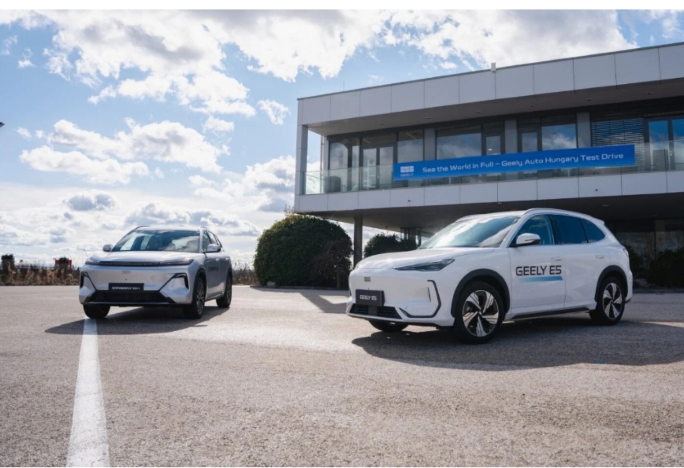 Zwei Geely Elektro-SUV stehen vor einem modernen Gebäude.