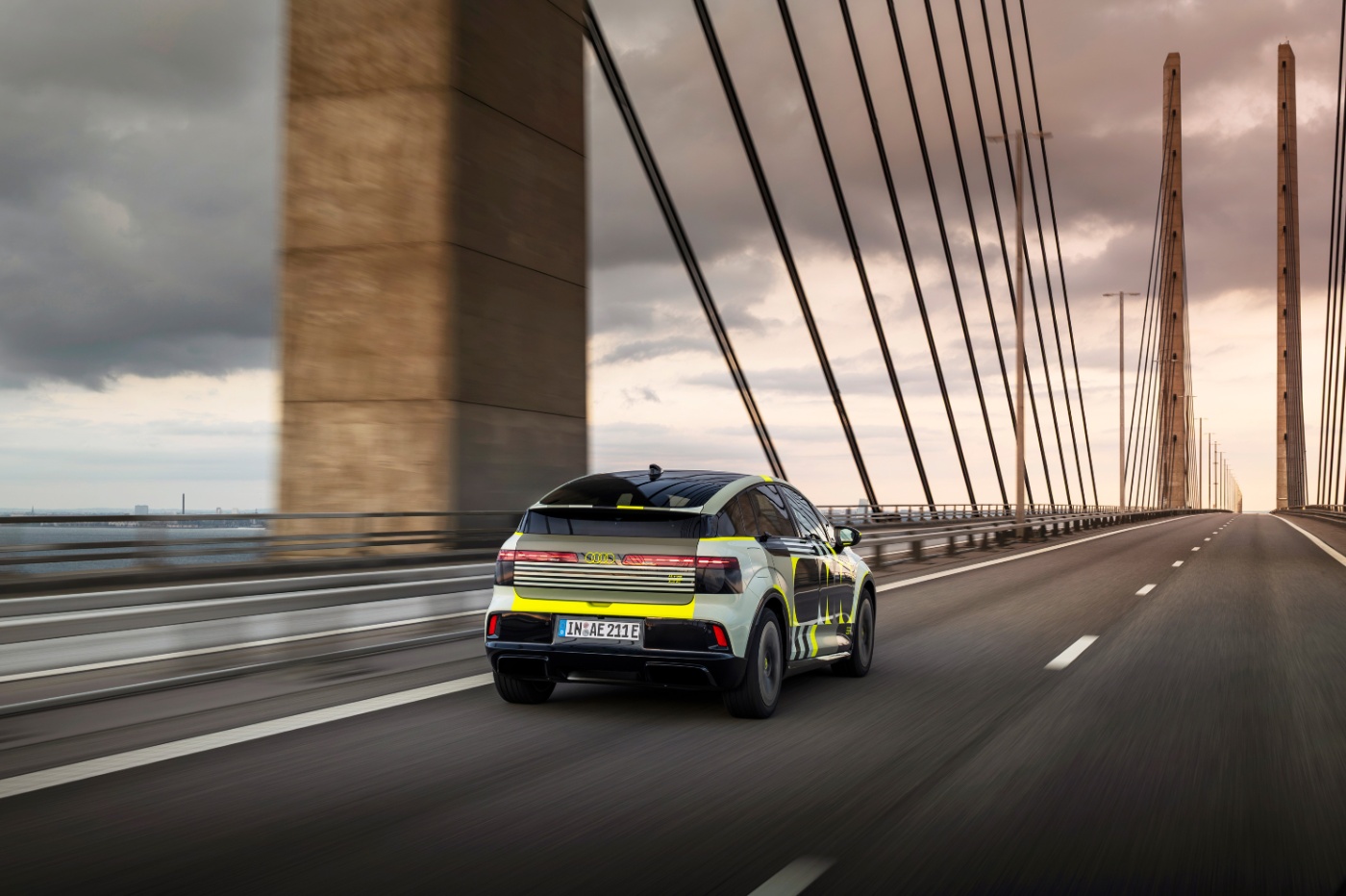 Audi prototype electric vehicle driving across a cable-stayed bridge.