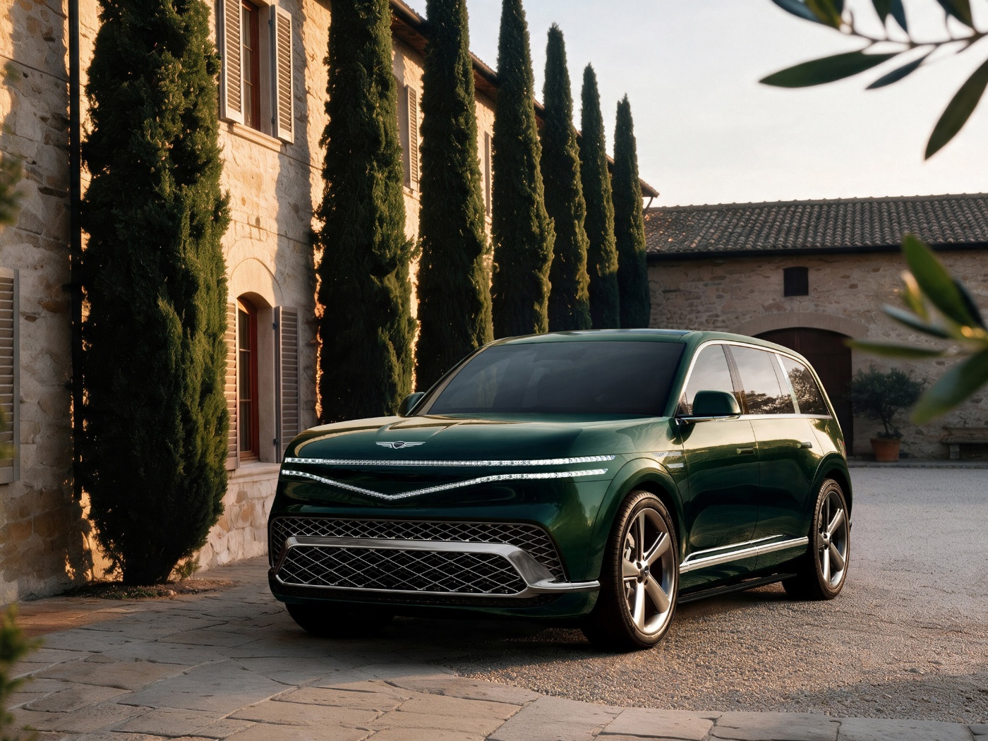 Grüner Genesis SUV vor einem von Zypressen gesäumten Gebäude.