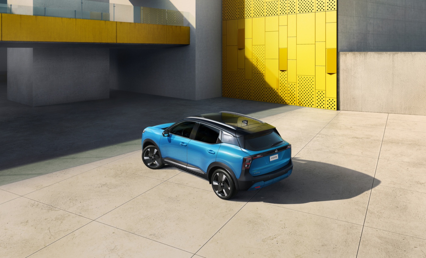 Blauer Nissan SUV vor einem modernen Gebäude mit gelbem Eingang.