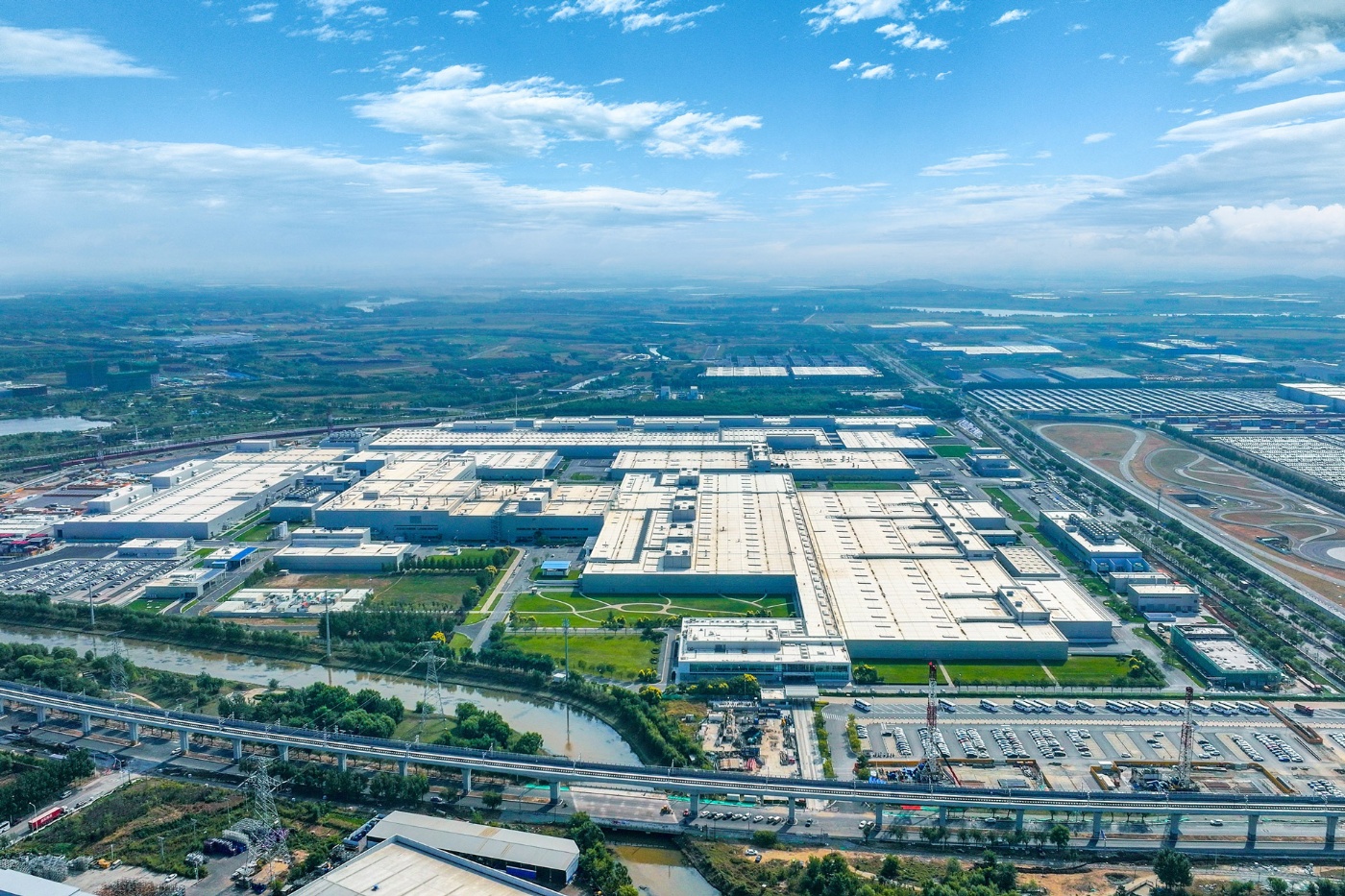 Aerial view of a large BMW factory complex with production halls, roads and surrounding greenery.