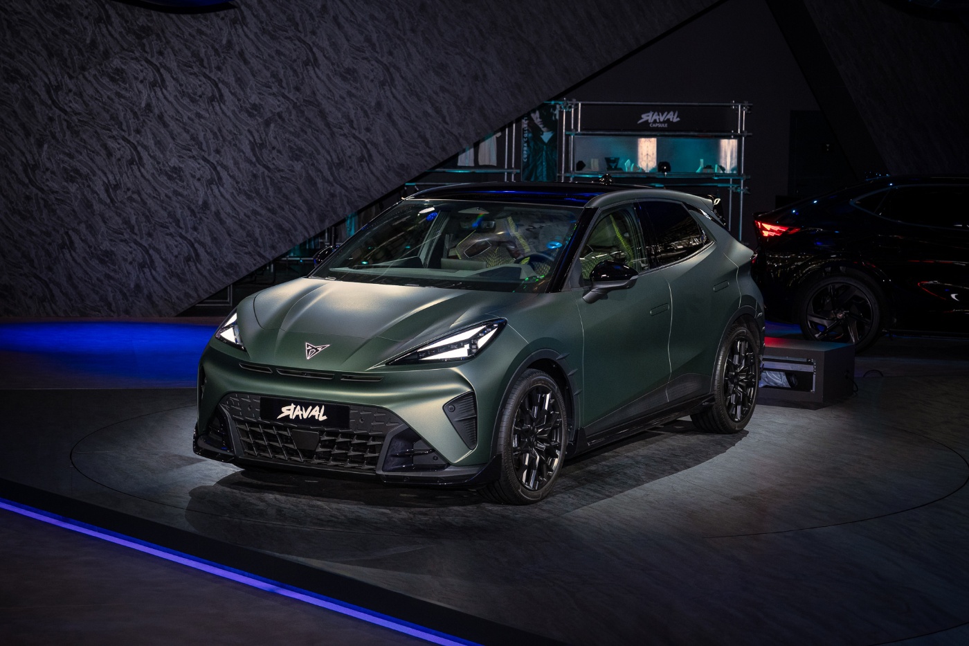 Mattgrüner CUPRA Raval als Elektroauto auf einer beleuchteten Bühne einer Automesse.