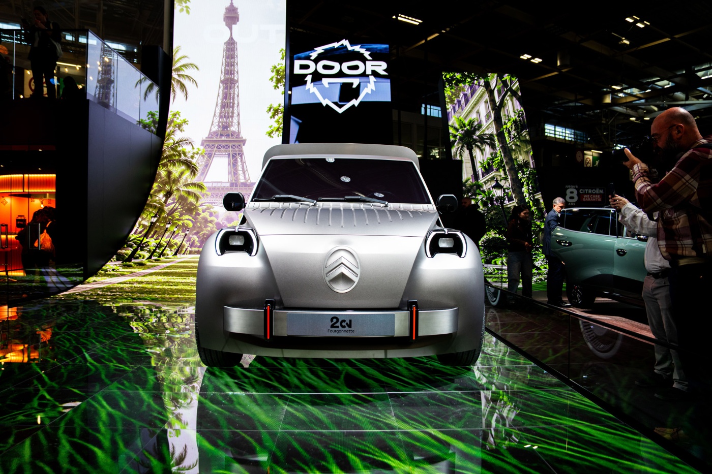 Frontansicht eines silbernen Citroën-Konzeptautos auf einer Automesse mit Eiffelturm im Hintergrund.