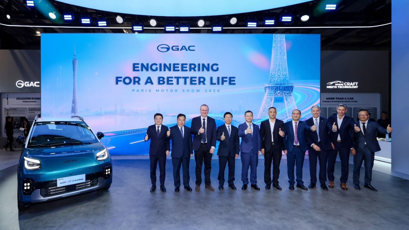 GAC-Vertreter posieren neben einem blauen Auto vor einer Leinwand auf einer Automesse.