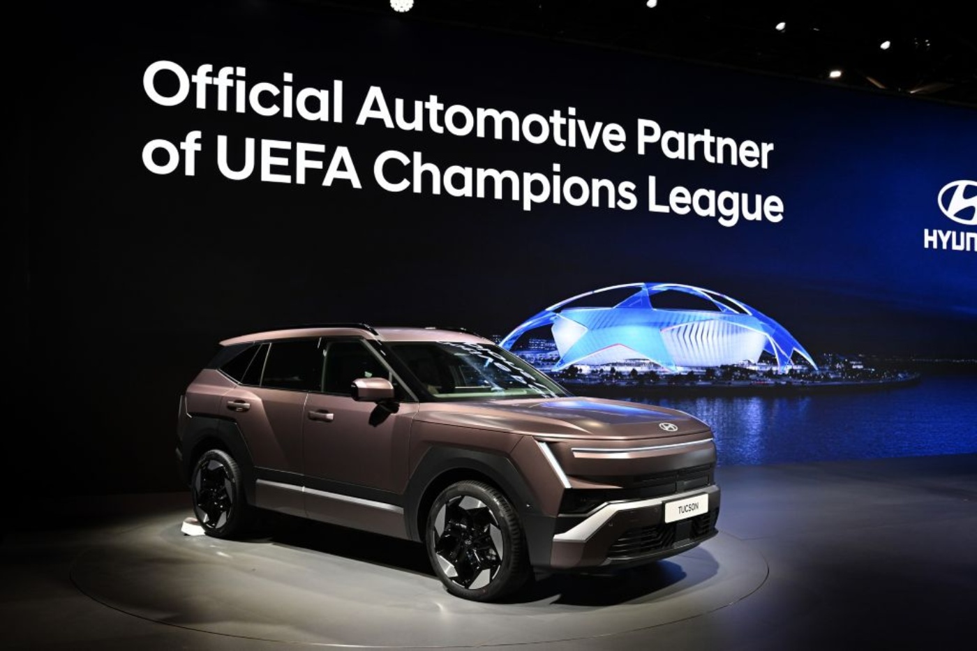 Hyundai Tucson vor einer Werbewand zur Partnerschaft mit der UEFA Champions League.