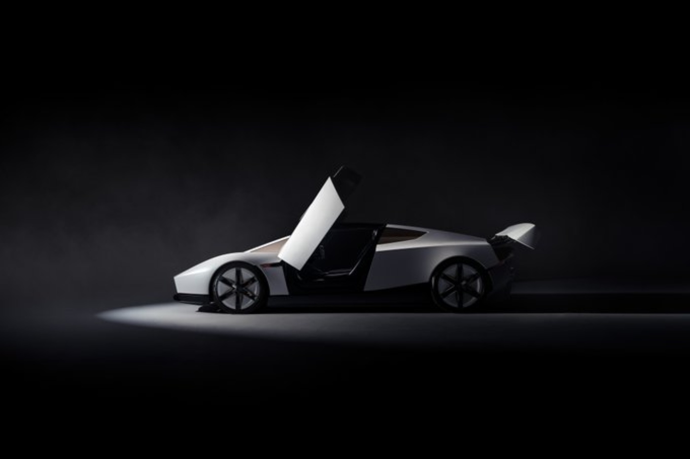 White Tesla Roadster with an open scissor door and a sleek, aerodynamic body, showcased in a dark studio setting.