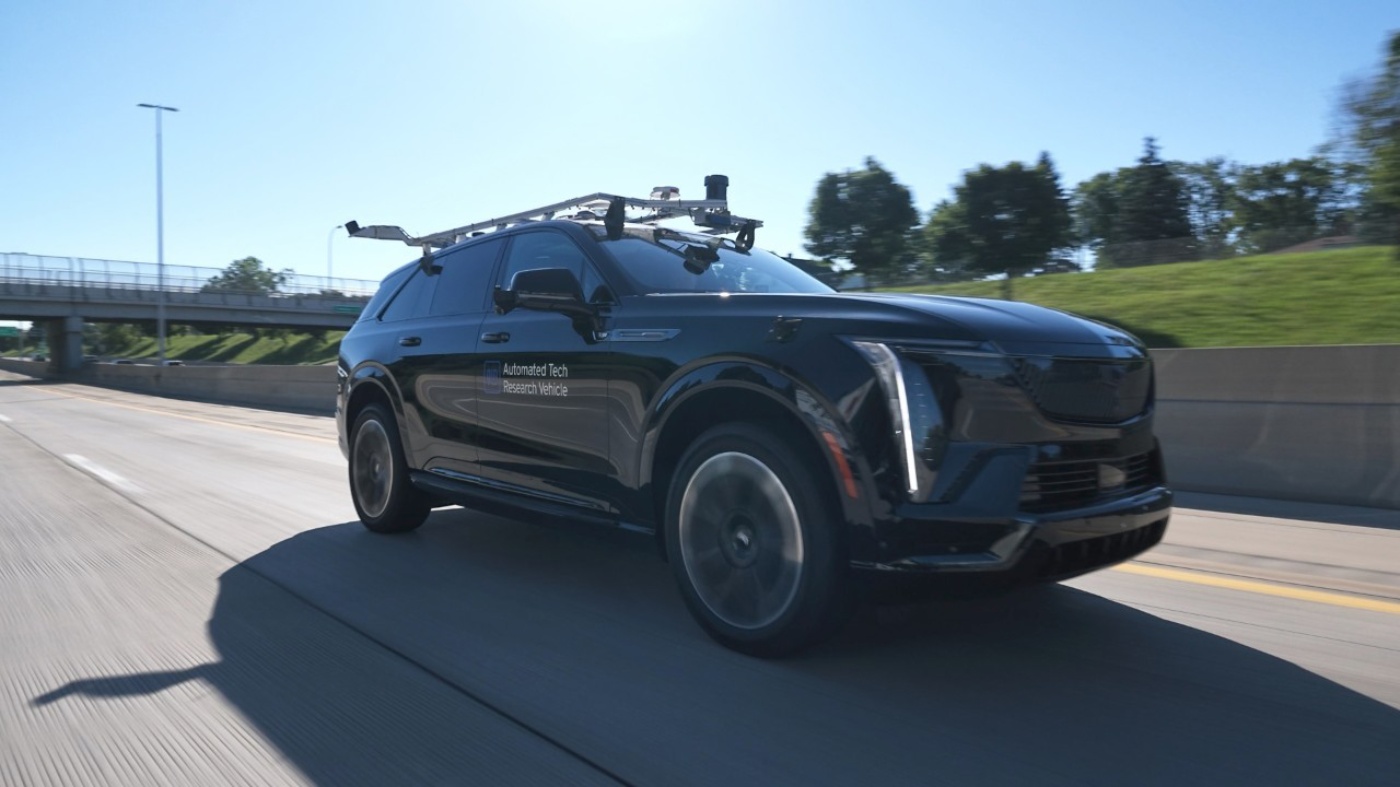 Black General Motors SUV with roof-mounted sensors driving on a test track.