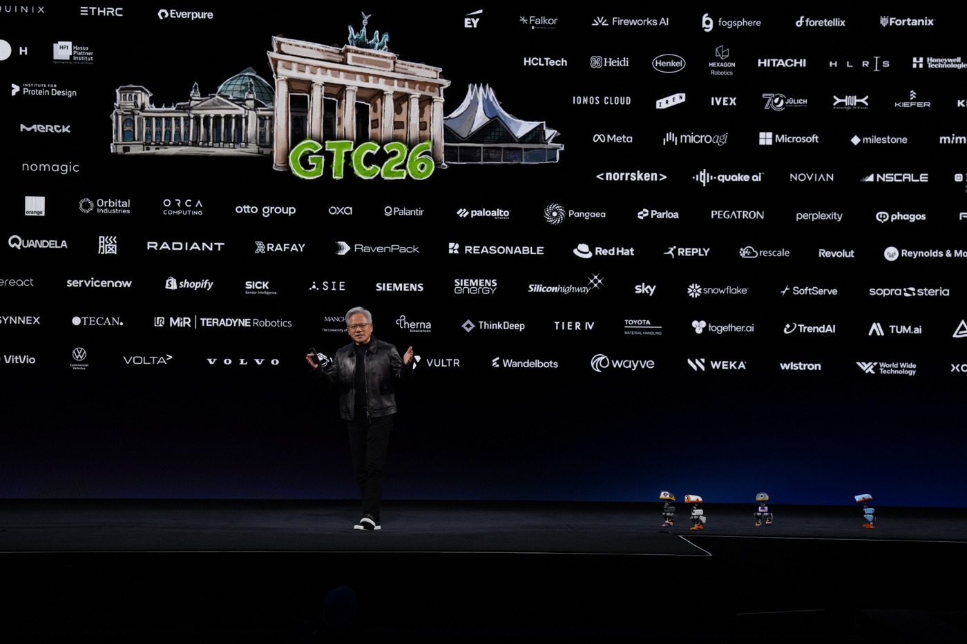 Redner auf der Bühne einer NVIDIA-Veranstaltung mit Brandenburger Tor und Partnerlogos auf einer Leinwand.